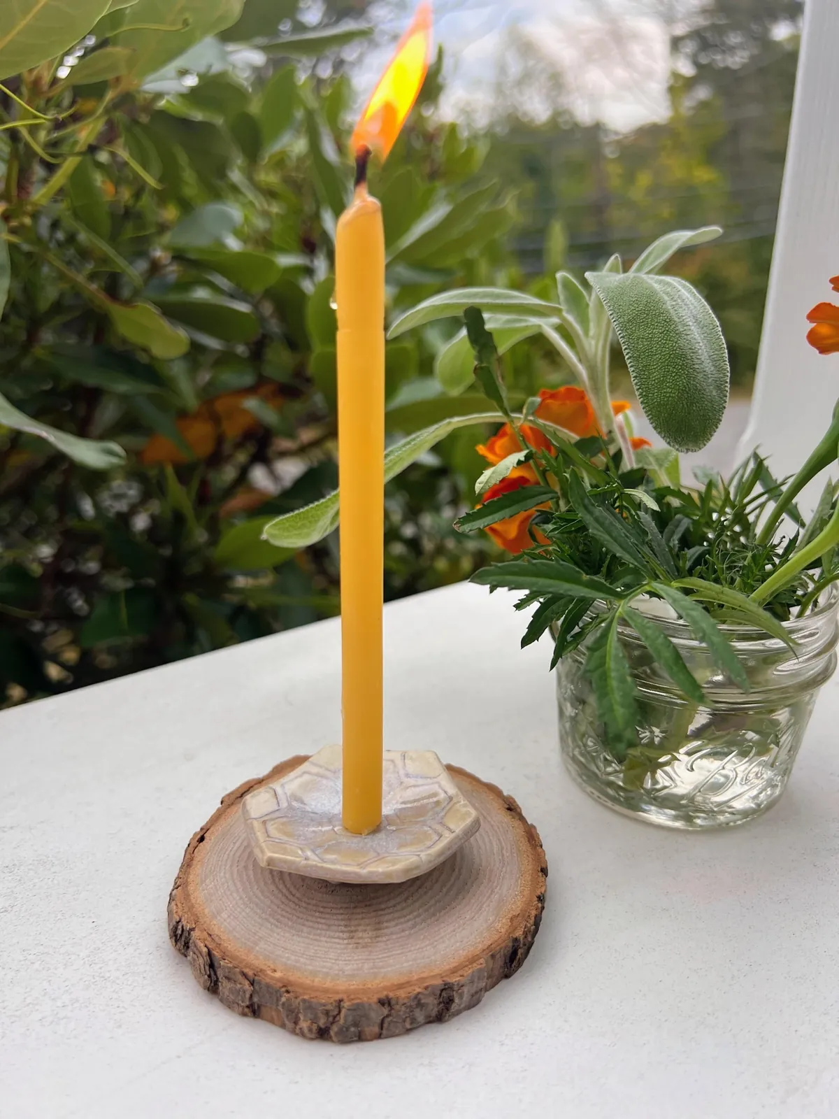 A lit beeswax taper on a porch in Rockport
